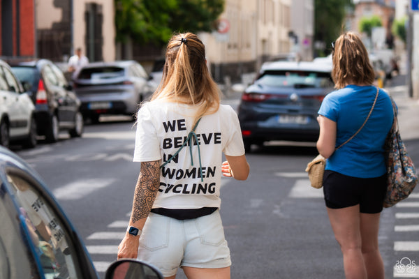 Femme dans la rue portant un t-shirt Wilma sur lequel il est écrit We Believe In Women Cycling