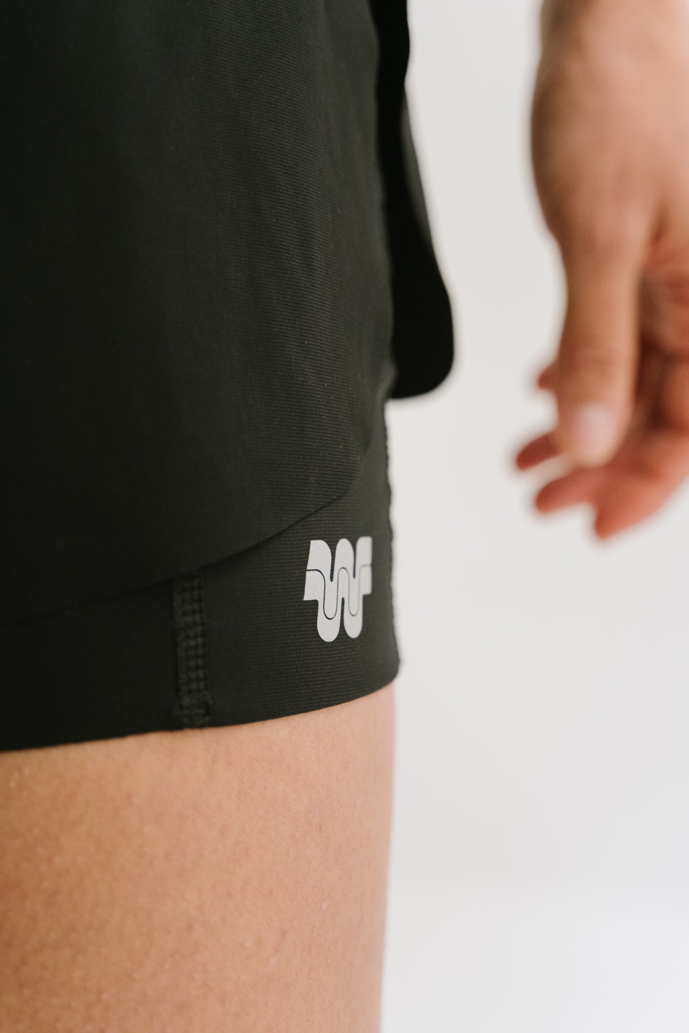 Zoom sur le monogramme Wilma élégamment placé sur la sous-couche gauche du short Rachel, ajoutant une touche de marque discrète. #color_Noir