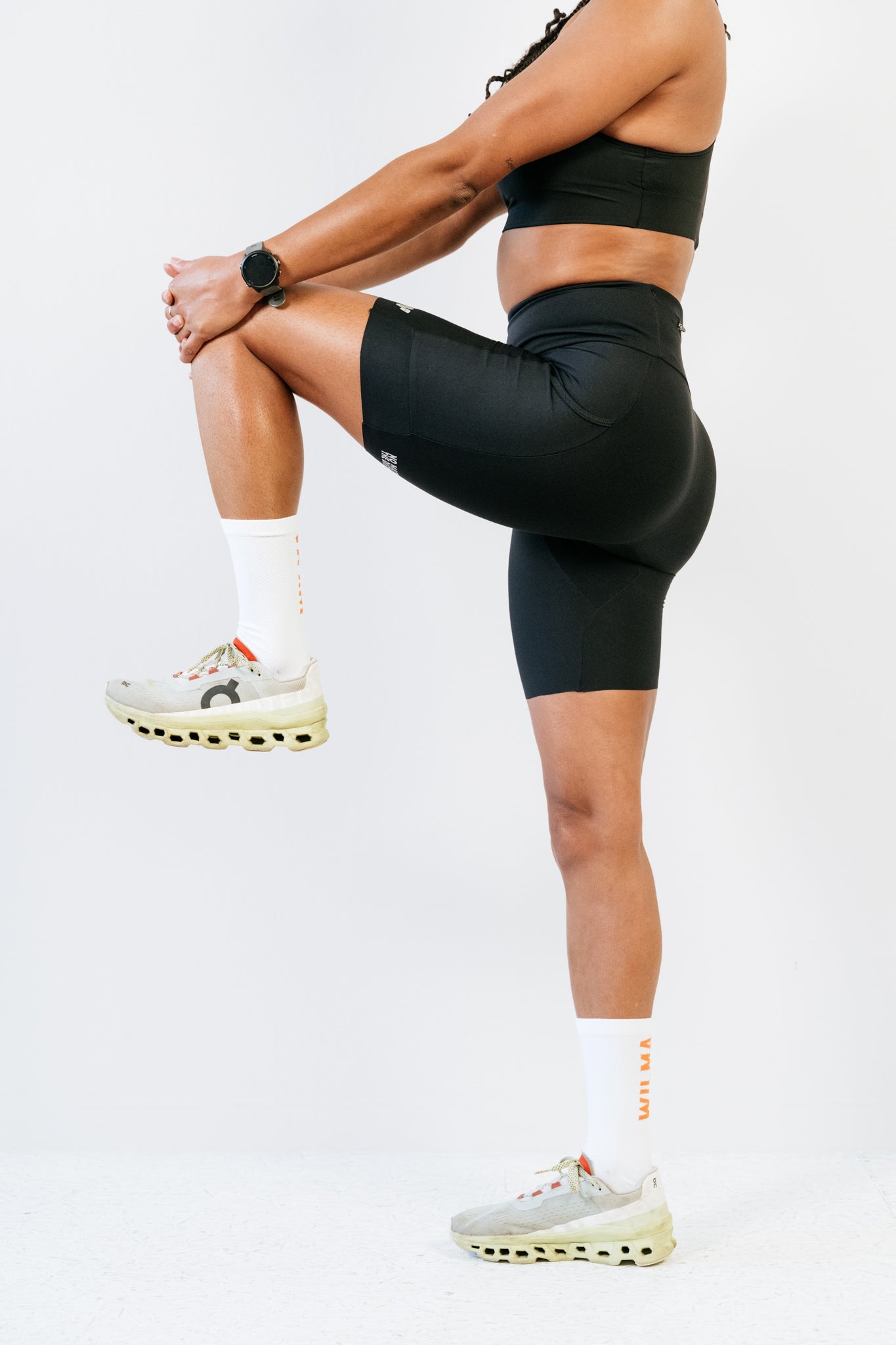 Short de running pour femme anti-frottement Nina noir vu de profil avec une jambe pliée