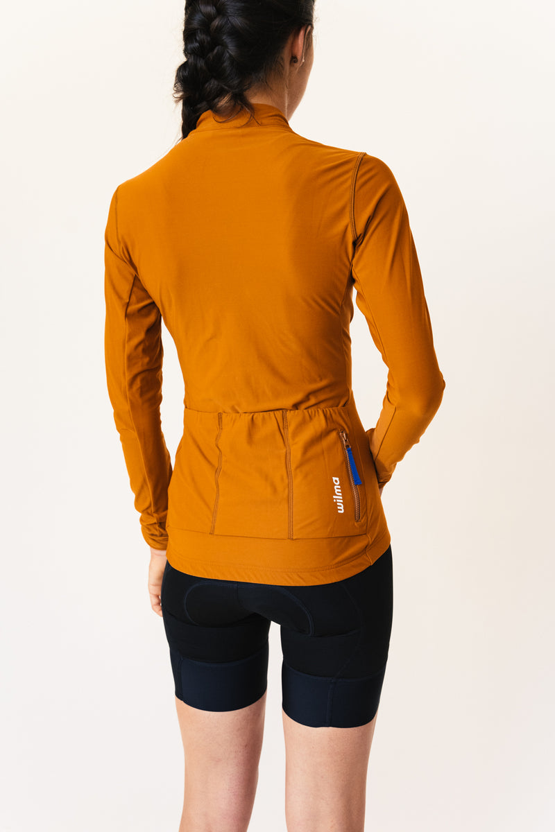 Femme portant un jersey de cyclisme couleur camel, vu de dos avec trois poches à l'arrière dont une zippée